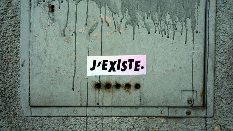 J'Existe sticker on a metal door